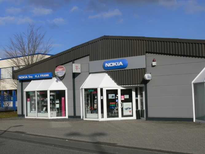 Modernes Nokia-Geschäft mit Schaufenstern und Handyshop im Gewerbegebiet bei Sonnenschein.